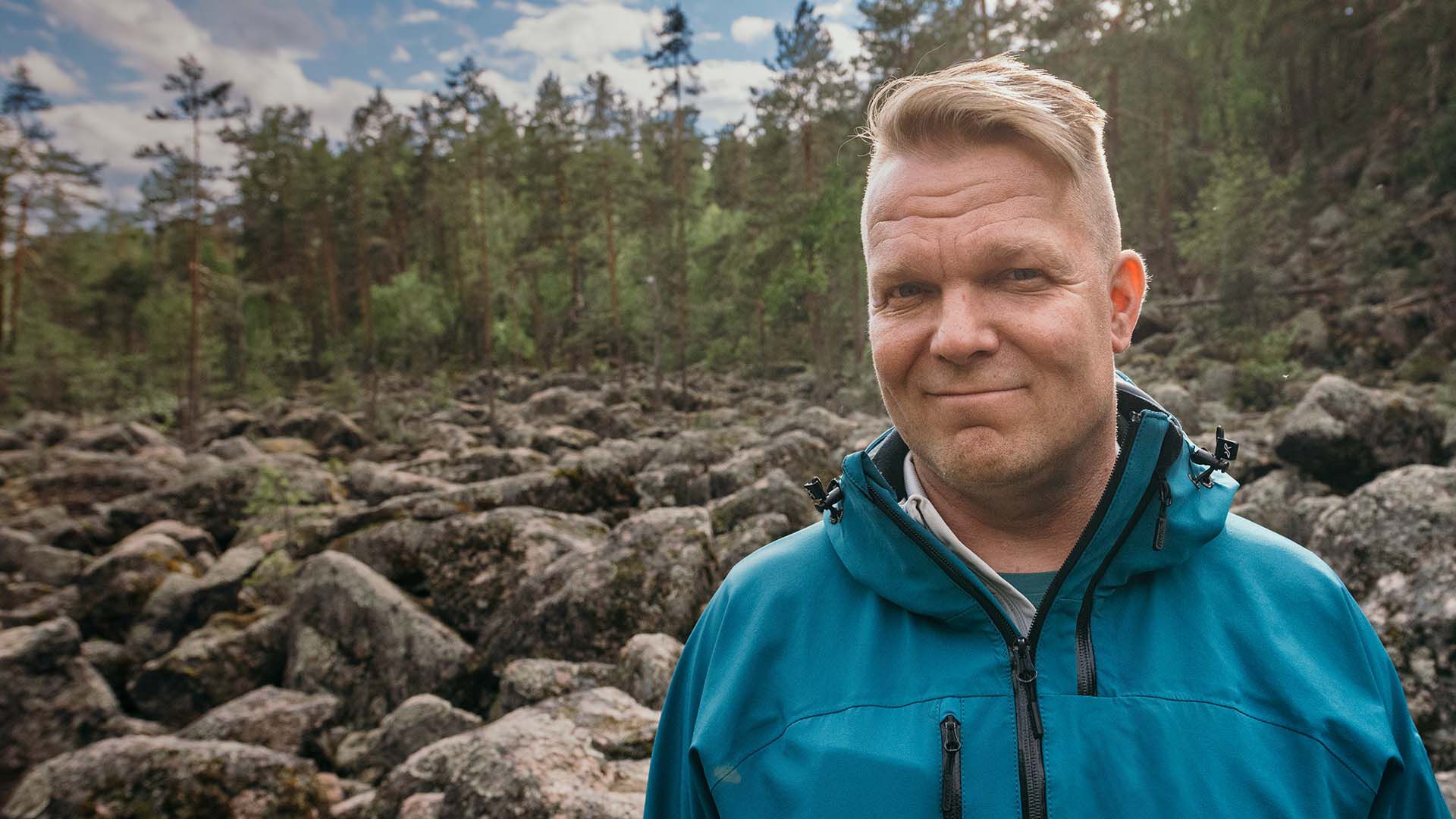 Mies hymyilee kameralle ulkona